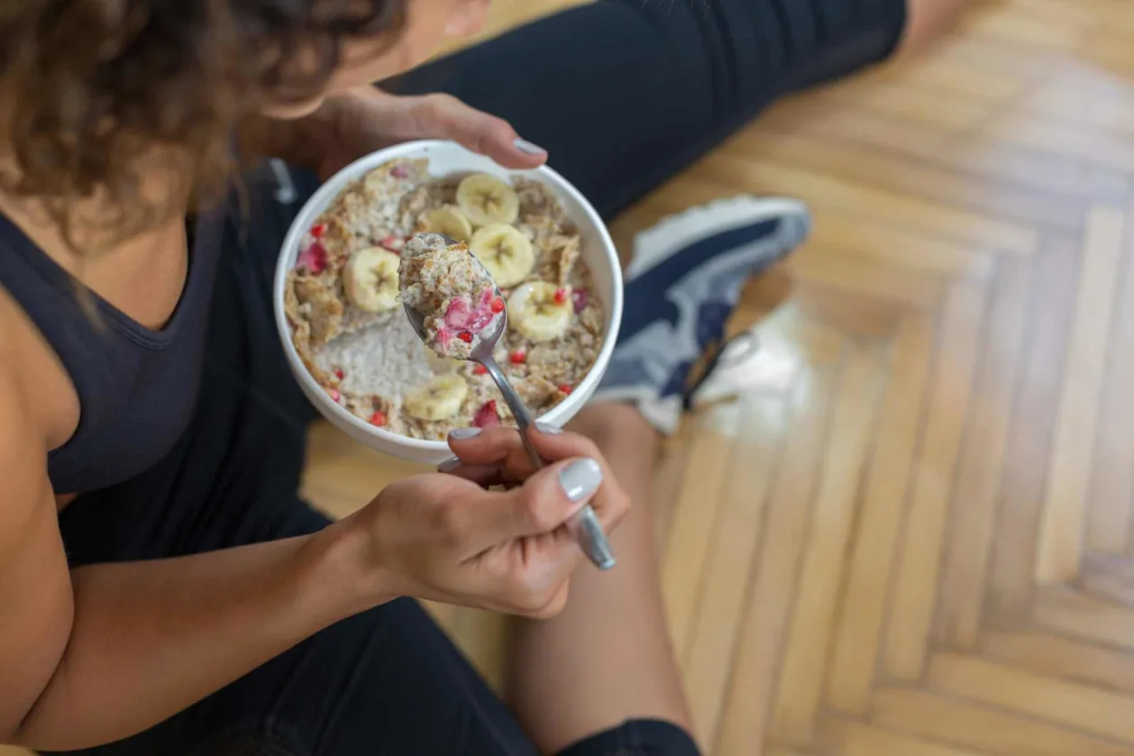 woman athlete eating bowl of oatmeal active nutrition concept